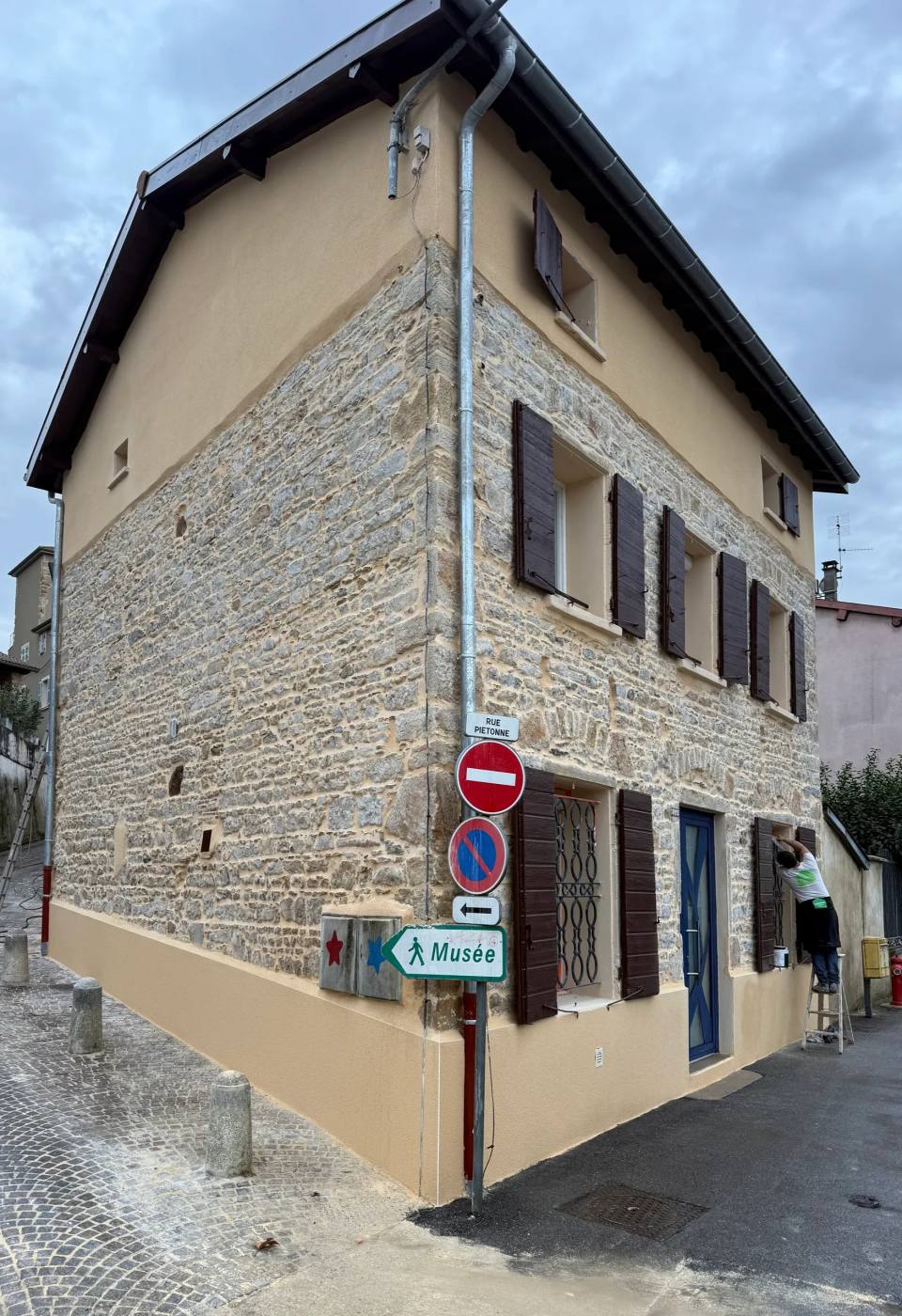 Pierre apparente en façade, pignon enduit ton sable.