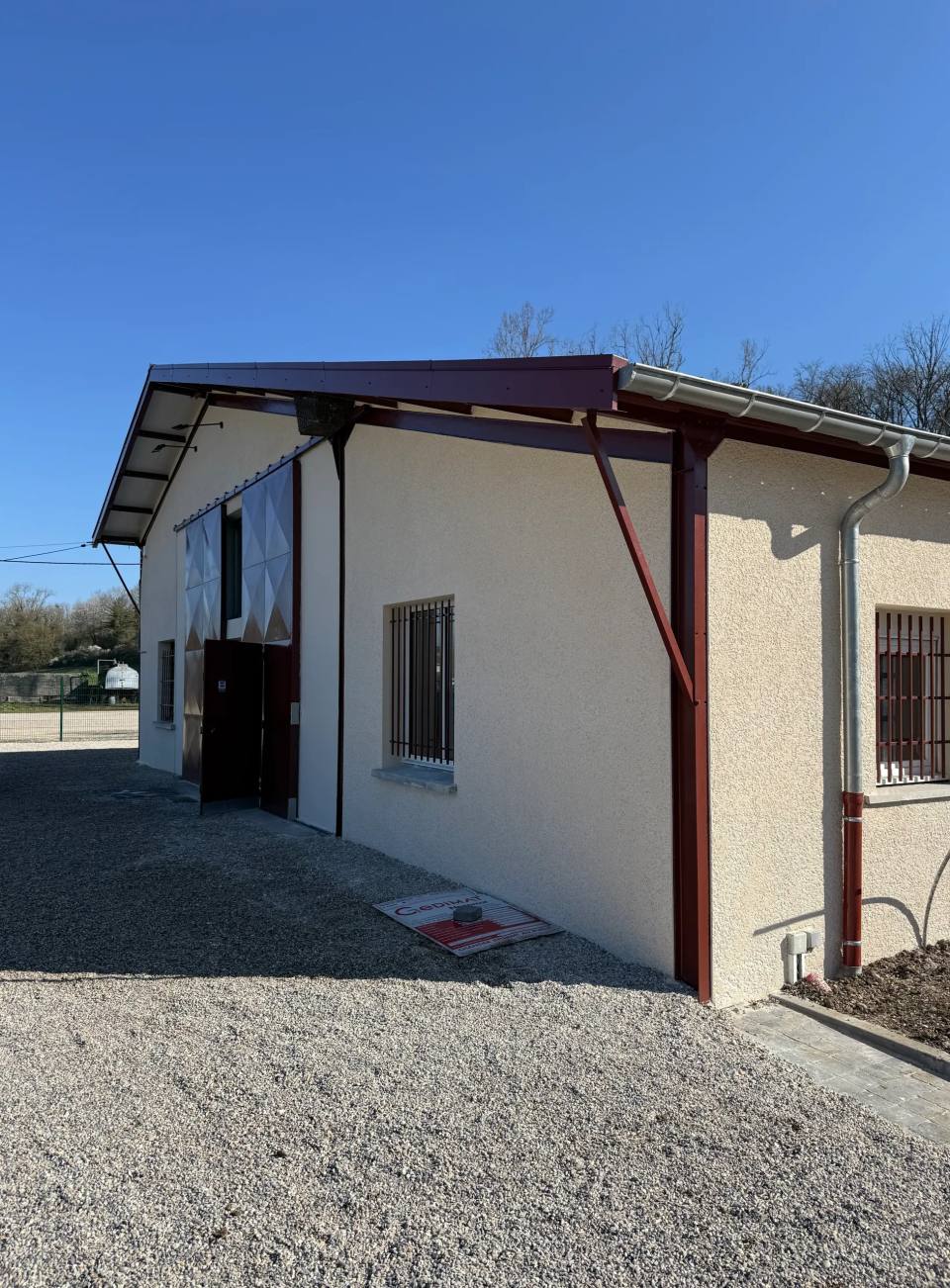 Bâtiment d’activité enduit, sous un auvent métallique.