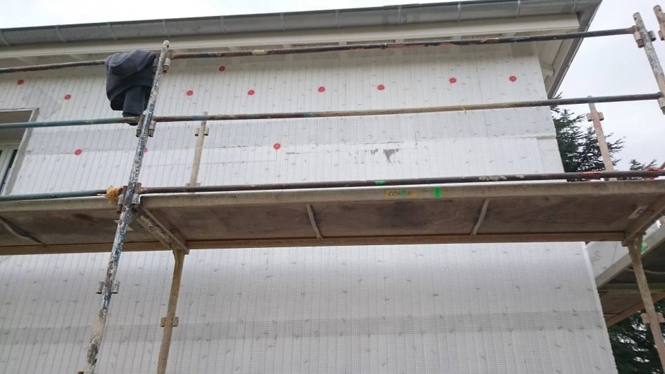 Panneaux isolants chevillés au mur, vus depuis l’échafaudage