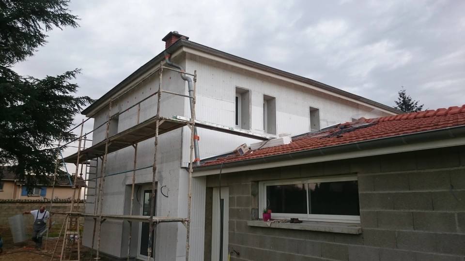 Pose des panneaux isolants blancs sur l’étage d’une maison, échafaudage en place
