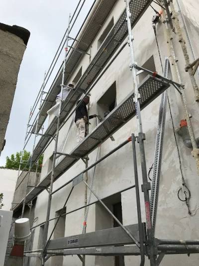 Façadiers appliquant le sous-enduit armé sur l’isolant, depuis l’échafaudage
