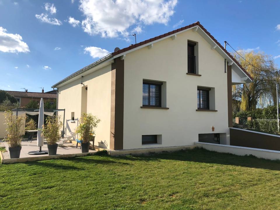 Maison crème aux chaînes d’angle brunes après ravalement, jardin engazonné