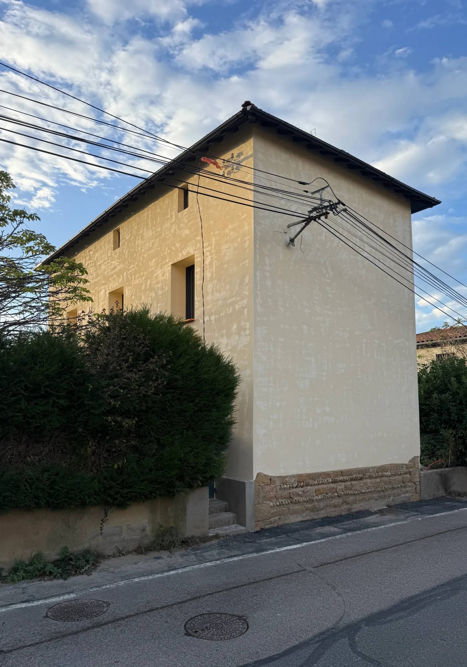 Maison ancienne enduite en ocre au-dessus d’un soubassement en pierre