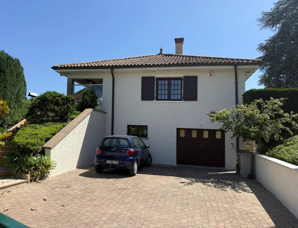 Villa blanche, volets bruns et murets enduits.