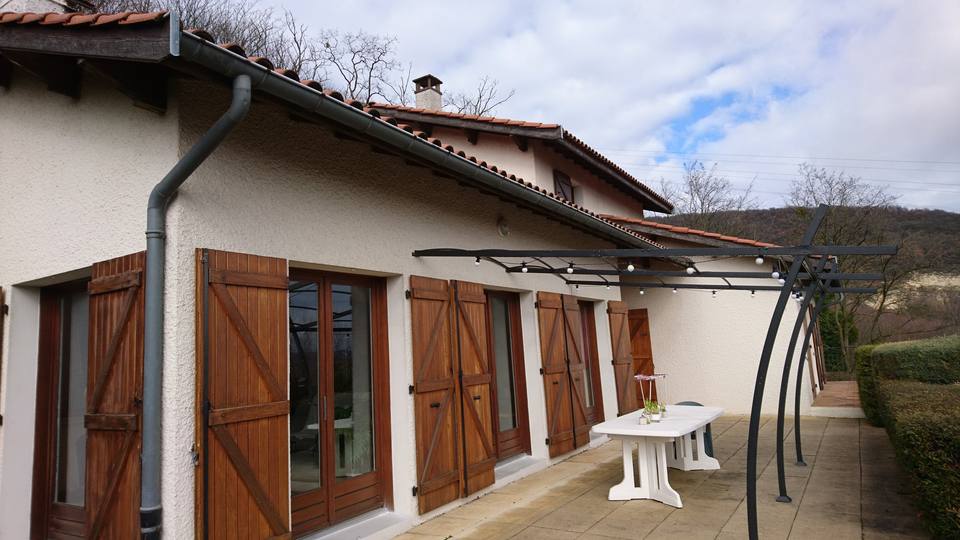 Façade claire et volets en bois naturel.